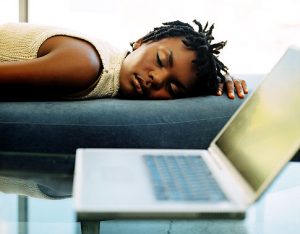 Young woman sleeping on a couch next to a laptop Original Filename: 57613069.jpg Gettyimages