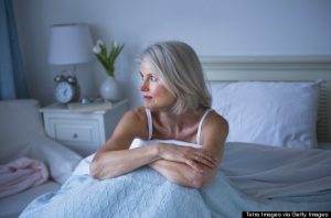 USA, New Jersey, Jersey City, Senior woman sitting in bed and suffering from insomnia